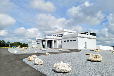 Huge modern white three-story stucco exterior home idea in Tampa with a mixed material roof and a white roof
