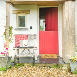 Inredning av en eklektisk entré, med vita väggar, en tvådelad stalldörr och en röd dörr