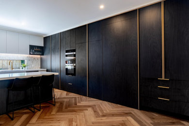 This is an example of a large contemporary open plan kitchen in Melbourne with a double-bowl sink, flat-panel cabinets, ceramic splashback, black appliances, dark hardwood floors, with island and brown floor.