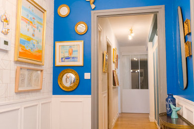 Cette image montre un hall d'entrée traditionnel de taille moyenne avec un mur bleu, un sol en bois brun, une porte simple, une porte blanche, un sol beige et boiseries.