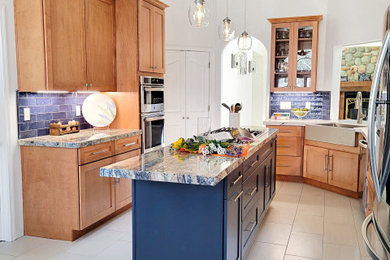 This is an example of a mid-sized country u-shaped eat-in kitchen in Sacramento with a farmhouse sink, shaker cabinets, blue cabinets, granite benchtops, blue splashback, ceramic splashback, stainless steel appliances, ceramic floors, with island, beige floor and blue benchtop.