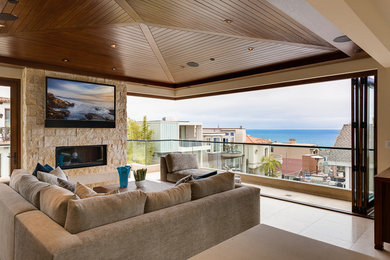 Family room - contemporary open concept family room idea in Orange County with beige walls, a stone fireplace and a wall-mounted tv