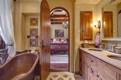 Large mediterranean master bathroom in San Francisco with beaded inset cabinets, medium wood cabinets, a freestanding tub, beige tile, stone tile, limestone benchtops, an alcove shower, a one-piece toilet, beige walls, porcelain floors and an undermount sink.