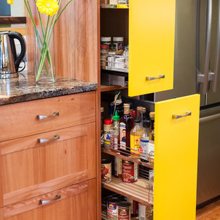 Zweizeilige, Kleine Eklektische Küche ohne Insel mit Vorratsschrank, Unterbauwaschbecken, flächenbündigen Schrankfronten, gelben Schränken, Granit-Arbeitsplatte, bunter Rückwand, Rückwand aus Keramikfliesen, Küchengeräten aus Edelstahl und braunem Holzboden in Portland