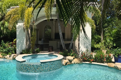 Example of an island style backyard stone patio kitchen design in Miami with a gazebo
