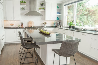 This is an example of a mid-sized beach style u-shaped kitchen in Bridgeport with an undermount sink, white cabinets, quartz benchtops, white splashback, ceramic splashback, stainless steel appliances, with island, brown floor, grey benchtop, recessed-panel cabinets and dark hardwood floors.