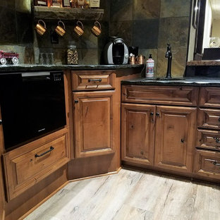 他の地域の中サイズのラスティックスタイルのおしゃれなウェットバー (アンダーカウンターシンク、レイズドパネル扉のキャビネット、中間色木目調キャビネット、御影石カウンター、マルチカラーのキッチンパネル、スレートの床、クッションフロア、マルチカラーの床) の写真