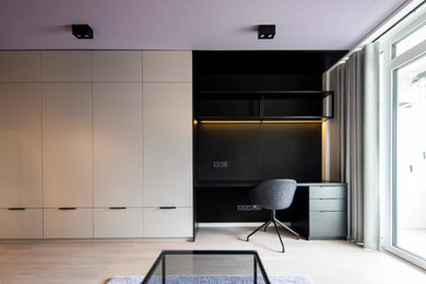 Imagen de estudio minimalista pequeño con paredes negras, suelo laminado y escritorio empotrado