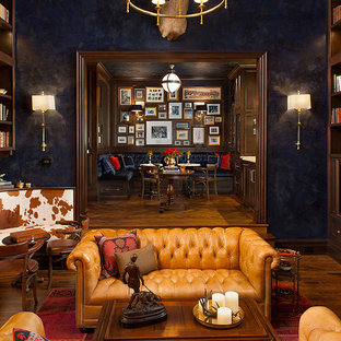 Modelo de despacho clásico, extra grande, con paredes azules, suelo de madera en tonos medios, escritorio empotrado, suelo marrón, chimenea tradicional y marco de chimenea de baldosas y/o azulejos