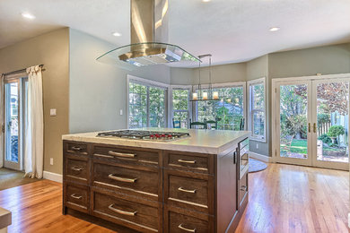 Example of a mid-sized trendy light wood floor eat-in kitchen design in San Francisco with recessed-panel cabinets, dark wood cabinets, marble countertops, stainless steel appliances and an island