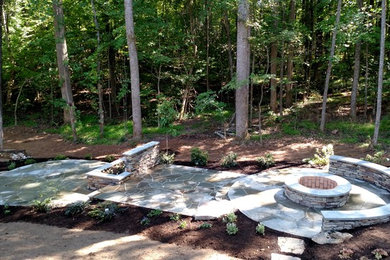 Mid-sized mountain style backyard stone patio photo in Raleigh with a fire pit and no cover