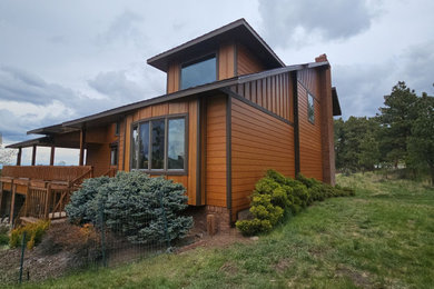 Rustic two-story concrete and board and batten gable roof idea in Denver