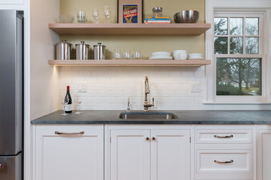 Small arts and crafts l-shaped light wood floor and brown floor enclosed kitchen photo in Detroit with an undermount sink, recessed-panel cabinets, white cabinets, soapstone countertops, white backsplash, ceramic backsplash, stainless steel appliances and no island