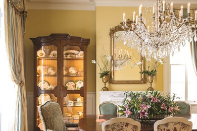 Inspiration for a large timeless medium tone wood floor and brown floor dining room remodel in New Orleans with yellow walls, a standard fireplace and a stone fireplace