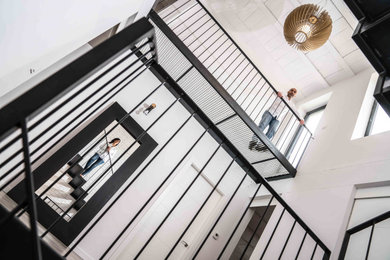 Foto de escalera en L actual de tamaño medio sin contrahuella con escalones de metal y barandilla de metal