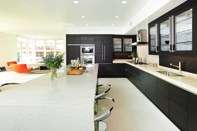 Photo of a large contemporary l-shaped open plan kitchen in San Francisco with flat-panel cabinets, panelled appliances, dark wood cabinets, quartz benchtops, beige splashback, stone tile splashback and with island.