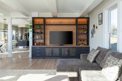 Diseño de sala de estar con barra de bar abierta de estilo de casa de campo con paredes blancas, suelo de madera clara, televisor independiente y suelo beige