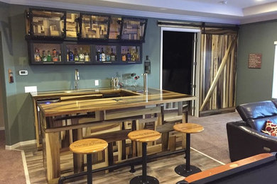 Large mountain style galley medium tone wood floor seated home bar photo in Orlando with recessed-panel cabinets, dark wood cabinets, wood countertops and green backsplash