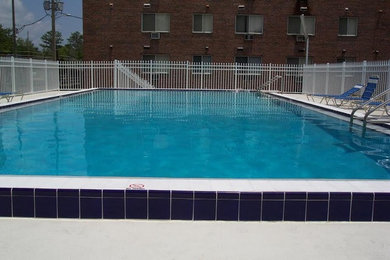 Ejemplo de piscina alargada clásica de tamaño medio rectangular en patio trasero con losas de hormigón
