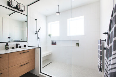 This is an example of a mid-sized contemporary master bathroom in Toronto with flat-panel cabinets, medium wood cabinets, an alcove shower, a one-piece toilet, white tile, subway tile, white walls, slate floors, an undermount sink, quartzite benchtops, grey floor, a hinged shower door and white benchtops.