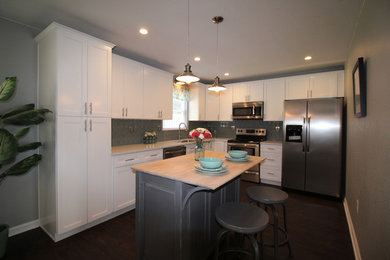 Inspiration for a mid-sized coastal l-shaped laminate floor and brown floor eat-in kitchen remodel in Other with an undermount sink, flat-panel cabinets, white cabinets, quartz countertops, blue backsplash, ceramic backsplash, stainless steel appliances and an island
