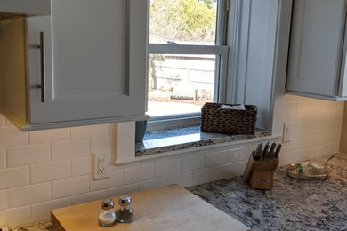 Small elegant galley dark wood floor and brown floor eat-in kitchen photo in New York with a double-bowl sink, shaker cabinets, white cabinets, solid surface countertops, white backsplash, ceramic backsplash, stainless steel appliances, no island and multicolored countertops