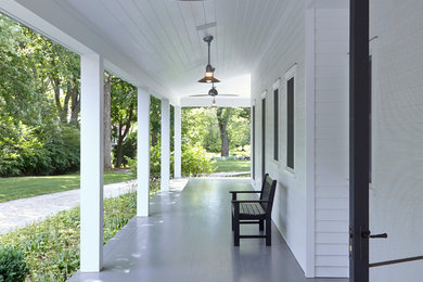 This is an example of a large transitional front porch design in New York with decking and a roof extension.