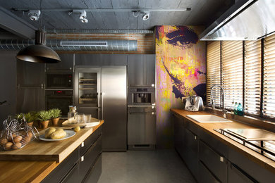 Inspiration for a mid-sized industrial galley eat-in kitchen in Moscow with a drop-in sink, wood benchtops, brown splashback, stainless steel appliances, multiple islands, grey floor and brown benchtop.