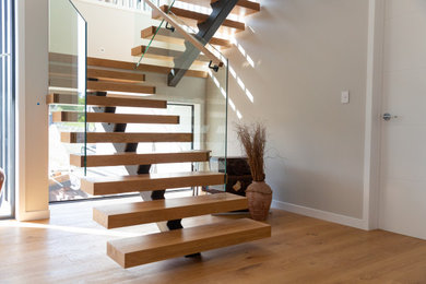 Foto de escalera suspendida moderna de tamaño medio sin contrahuella con escalones de madera y barandilla de varios materiales