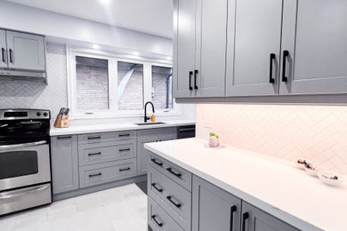 Small trendy galley ceramic tile, gray floor and exposed beam enclosed kitchen photo in Toronto with an undermount sink, flat-panel cabinets, gray cabinets, marble countertops, white backsplash, ceramic backsplash, black appliances, no island and white countertops