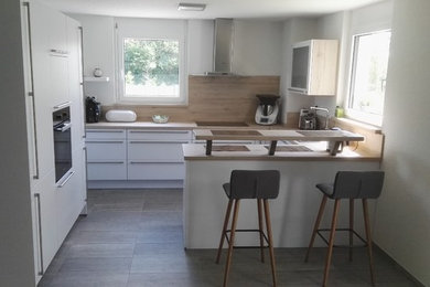 Идея дизайна: прямая кухня-гостиная в современном стиле с белыми фасадами, столешницей из ламината, техникой под мебельный фасад и полуостровом