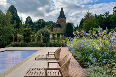Photo of a medium sized farmhouse rectangular swimming pool in Surrey with with pool landscaping and natural stone paving.