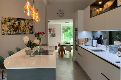 Design ideas for a contemporary kitchen/diner in London with a single-bowl sink, white cabinets, quartz worktops, mirror splashback, stainless steel appliances, vinyl flooring, an island, grey floors and white worktops.