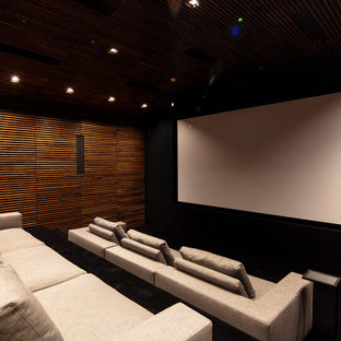 Aménagement d'une très grande salle de cinéma moderne fermée avec un mur noir, un écran de projection et un sol noir.