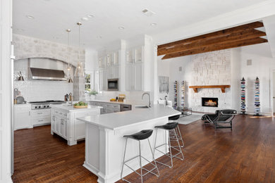 Large elegant u-shaped dark wood floor, brown floor and exposed beam open concept kitchen photo in Dallas with a single-bowl sink, shaker cabinets, white cabinets, quartz countertops, white backsplash, ceramic backsplash, stainless steel appliances, an island and white countertops