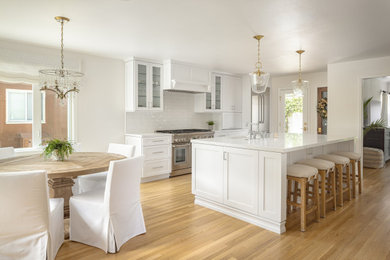 Inspiration for a huge french country eat-in kitchen remodel in Los Angeles with an undermount sink, white cabinets, quartz countertops, white backsplash, porcelain backsplash, stainless steel appliances and an island