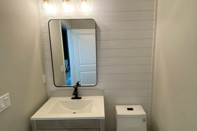 Powder room - mid-sized modern ceramic tile powder room idea in Orlando with shaker cabinets, gray cabinets, a one-piece toilet, beige walls, an integrated sink, white countertops and a freestanding vanity