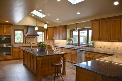 Open concept kitchen - large traditional u-shaped ceramic tile open concept kitchen idea in Milwaukee with a double-bowl sink, shaker cabinets, medium tone wood cabinets, granite countertops, beige backsplash, stone tile backsplash, stainless steel appliances and two islands