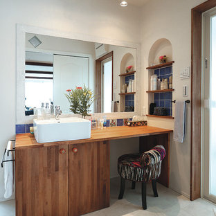 他の地域のカントリー風おしゃれなトイレ・洗面所 (フラットパネル扉のキャビネット、中間色木目調キャビネット、白い壁、ベッセル式洗面器、木製洗面台、ベージュの床) の写真