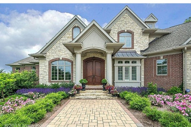 Example of a huge classic beige two-story stone exterior home design in Other with a shingle roof