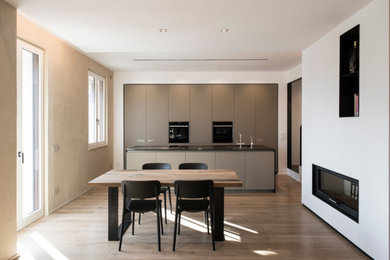 Foto di una cucina moderna di medie dimensioni con lavello integrato, ante lisce, ante beige, top in superficie solida, elettrodomestici neri, parquet chiaro, pavimento marrone e top nero