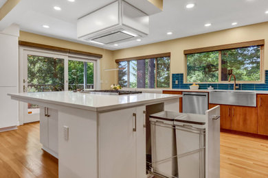 Example of a transitional brown floor eat-in kitchen design in Portland with dark wood cabinets, blue backsplash, glass tile backsplash, stainless steel appliances, an island and white countertops