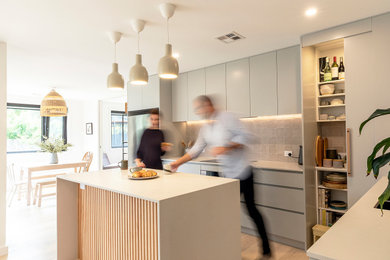 Design ideas for a small contemporary l-shaped open plan kitchen in Canberra - Queanbeyan with a double-bowl sink, flat-panel cabinets, grey cabinets, composite countertops, beige splashback, ceramic splashback, stainless steel appliances, light hardwood flooring and an island.