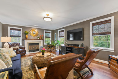 Example of a transitional enclosed medium tone wood floor, brown floor and wallpaper family room design in DC Metro with brown walls, a standard fireplace, a stone fireplace and a wall-mounted tv