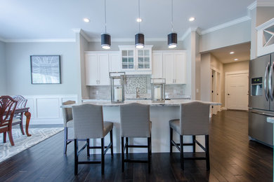 Example of a mid-sized transitional single-wall dark wood floor eat-in kitchen design in Other with recessed-panel cabinets, white cabinets, granite countertops, stone tile backsplash, stainless steel appliances and an island