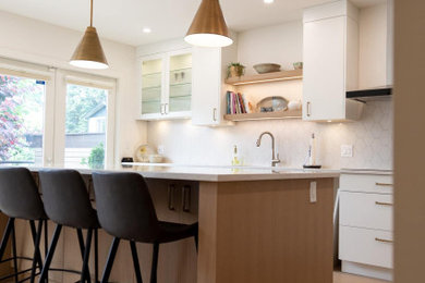 Example of a large 1960s l-shaped eat-in kitchen design in Vancouver with an undermount sink, flat-panel cabinets, light wood cabinets, white backsplash, stone tile backsplash, stainless steel appliances and an island