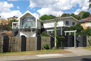 Photo of a contemporary two-storey white house exterior in Melbourne with metal siding, a gable roof and a metal roof.