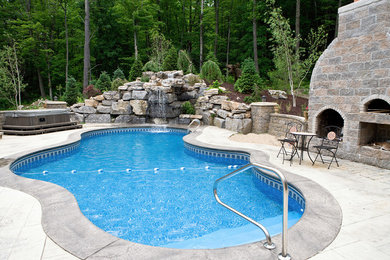 Inspiration for a backyard custom-shaped pool in Boston with a water feature and stamped concrete.