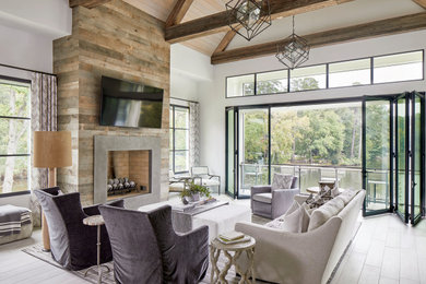 Transitional light wood floor, beige floor, exposed beam, vaulted ceiling and wood ceiling living room photo in Atlanta with white walls, a standard fireplace, a concrete fireplace and a wall-mounted tv