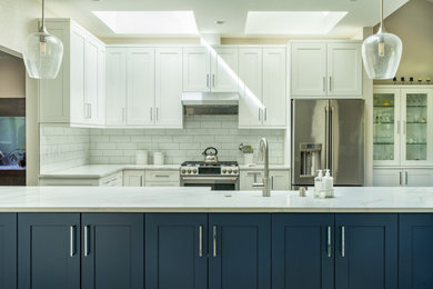 Example of a mid-sized trendy l-shaped eat-in kitchen design in Seattle with a farmhouse sink, shaker cabinets, white cabinets, quartz countertops, white backsplash, subway tile backsplash, stainless steel appliances, a peninsula and white countertops